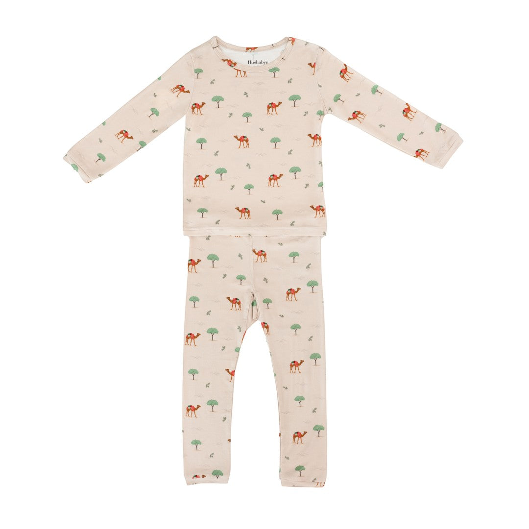 Hushabye camel print bamboo rayon pajamas for kids. Long sleeve top and pants in a light beige with a desert camel and tree pattern.