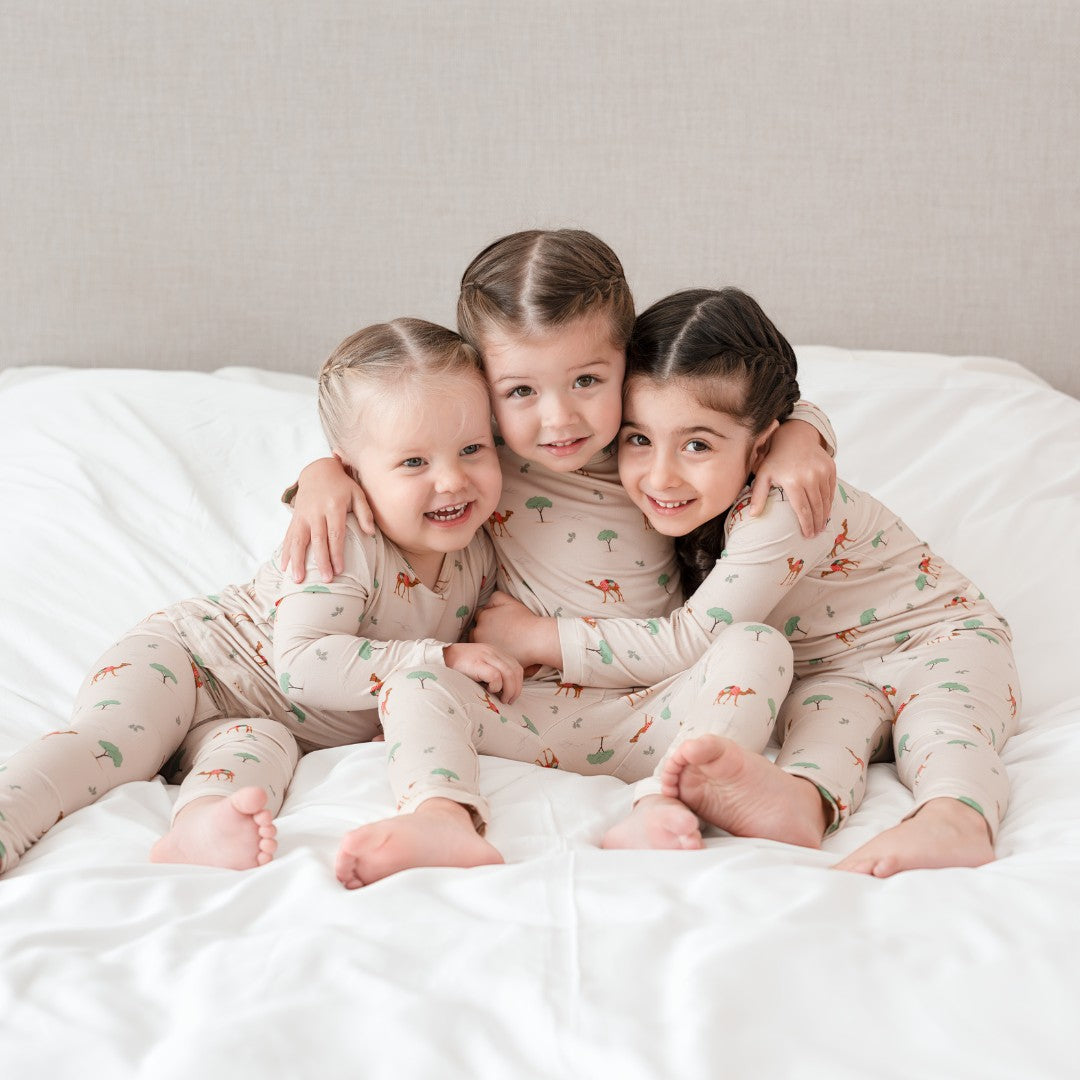 Hushabye camel print bamboo rayon pajamas on three children sitting on a white bed. Soft, breathable, OEKO-TEX® certified.